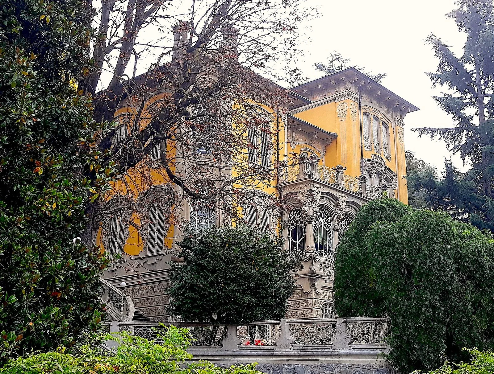 Villa Scott, villa liberty gialla con decorazioni in pietra, balconi in ferro battuto e grande vetrata, circondata da alberi in Borgo Po a Torino